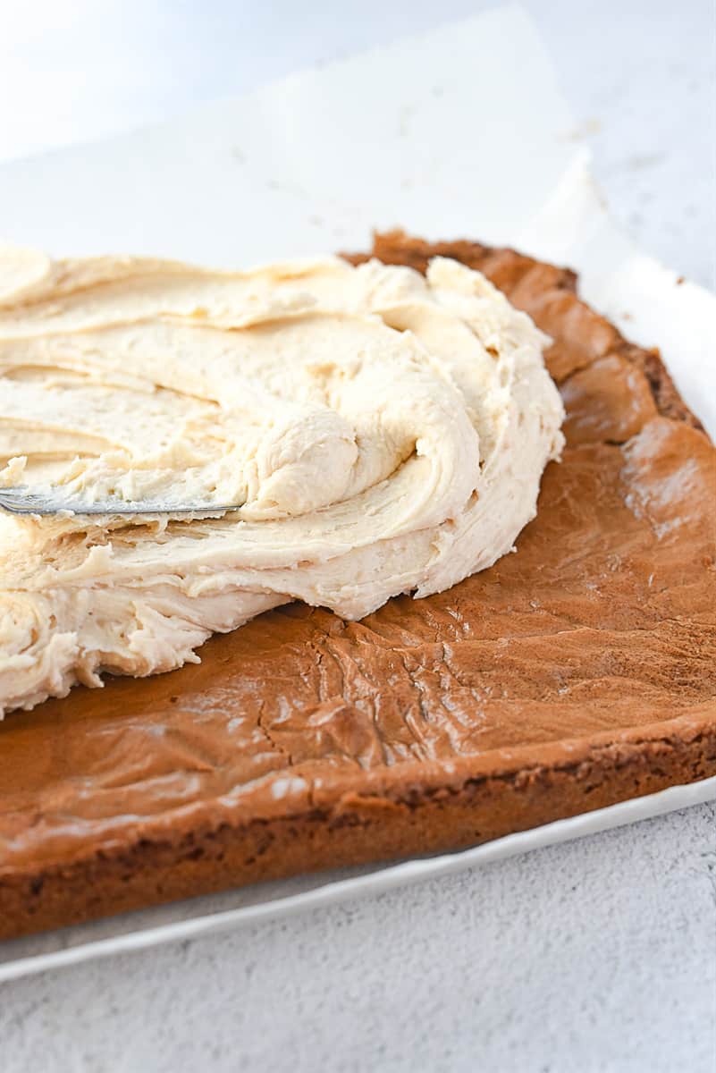 spreading brown butter frosting on brownies